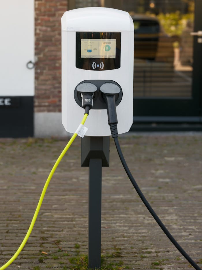 Close-up image of a modern electric vehicle charging station outdoors with two cables connected.